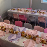 Dining room with tables set for a meal, pink chairs, and decorative elements.