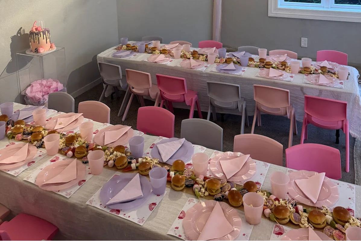 Dining room with tables set for a meal, pink chairs, and decorative elements.