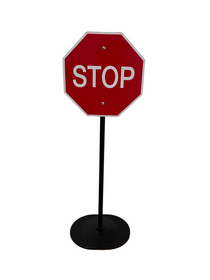 Red stop sign on a black stand against a white wall.