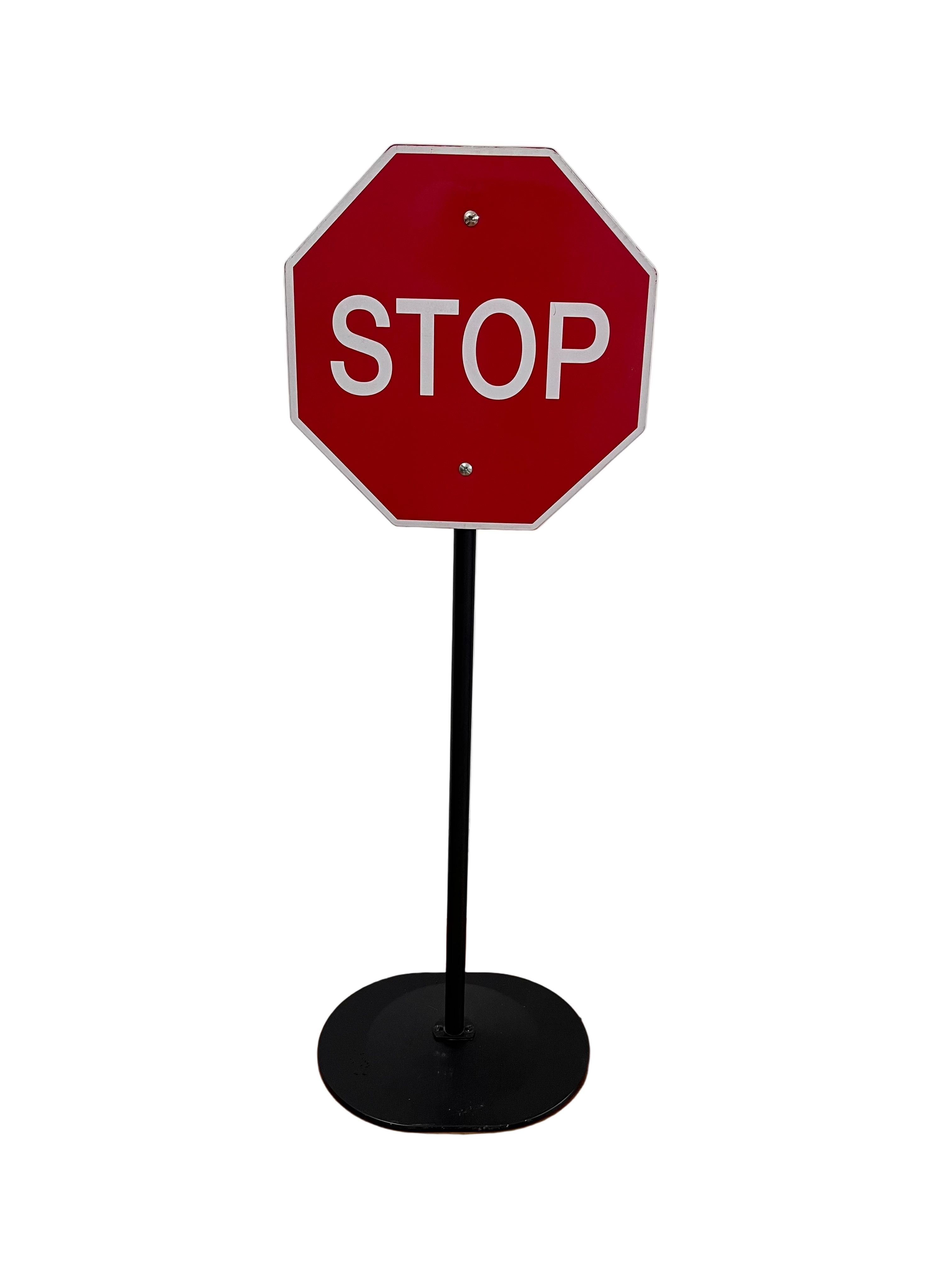 Red stop sign on a black stand against a white wall.