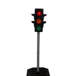 Miniature traffic light on a stand against a white wall.