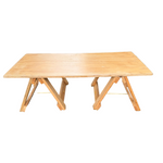 Wooden table on a grassy area with a garden and house in the background