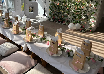 Decorated room with tables set for a celebration, floral wall, and large number '16'.