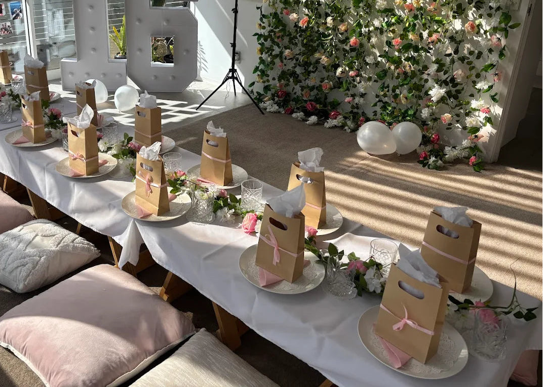 Decorated room with tables set for a celebration, floral wall, and large number '16'.
